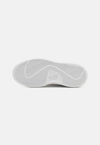 Witte sneakerzool met een visgraatpatroon en een gestructureerd oppervlak. Geperst logo en zichtbare 'non-marking' label.