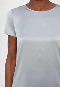 Světle modrý krátký rukáv top vyrobený z hladké látky s kulatým výstřihem a jemným leskem, s minimálním švem a bez viditelných vzorů.