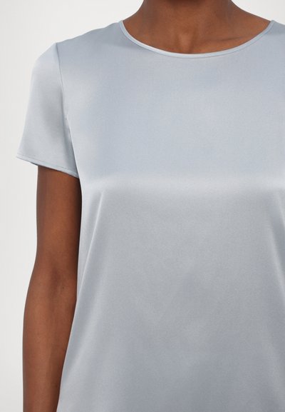 Top azul claro de manga curta, feito de tecido suave com decote redondo e leve brilho, apresentando costuras mínimas e sem padrões visíveis.