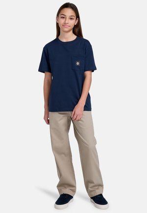 Marineblå kortærmet t-shirt med en brystlomme og et lille logo-patch, parret med beige vidde bukser og mørke sneakers.