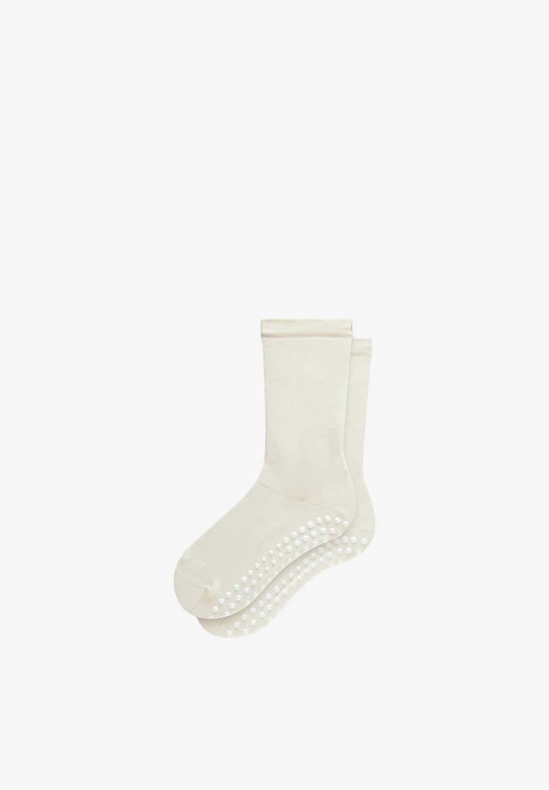 Chaussettes en coton beige avec une surface texturée et un motif de points en silicone antidérapants sur les semelles pour une meilleure adhérence.