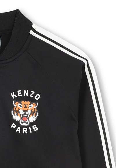 Felpa nera con grafica di una tigre e testo "KENZO PARIS". Presenta strisce laterali bianche e un colletto a costine. Tessuto dal tocco morbido.