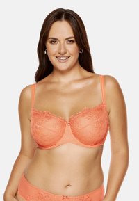 Jasnoróżowy koronkowy stanik z haftem w kształcie kwiatów, z fiszbinami i regulowanymi ramiączkami. Posiada małą dekoracyjną kokardkę na środku przodu.