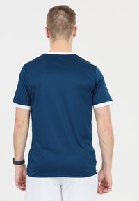 Mörkblå tränings t-shirt med korta vita ärmar och krage, designad i ett slätt, lätt material, med en figurnära silhuett.