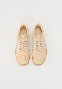 Beige sneakers med mesh- og ruskindmateriale, med lyseblå striber, snørelukning og en gummirunner.