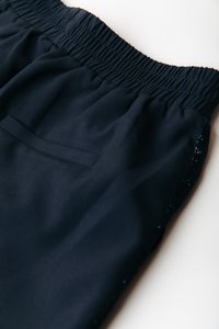 Tumesinine lühike püksid elastse vöökohaga, sileda tekstuuriga ja väikese taskuga ees, mis lisab funktsionaalsust.