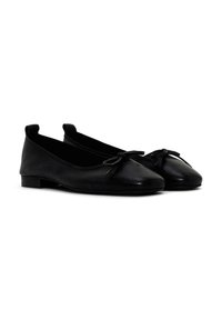 Bailarinas de cuero negro con un acabado texturizado, punta redondeada y pequeño detalle de lazo en la parte delantera, con un tacón bajo y plano.