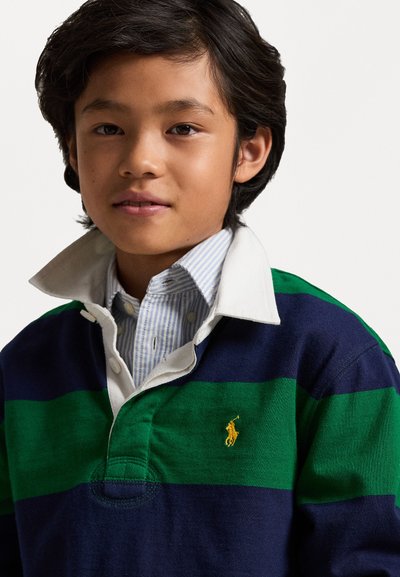 Ραβδωτό ριγέ ρούχο ράγκμπι σε ναυτικό μπλε, πράσινο και λευκό χρώμα, με λευκό γιακά και κεντημένο λογότυπο στο αριστερό στήθος.