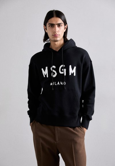 Mustapaitainen huppari, jossa on valkoiset kirjaimet "MSGM MILANO". Valmistettu pehmeästä, teksturoidusta kankaasta. Sisältää etuläppeen ja säädettävän nyörihupparin.