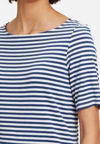 Randig kortärmad topp med ett blått och vitt mönster, rundad halsringning och ett mjukt tyg med lätt stretch.