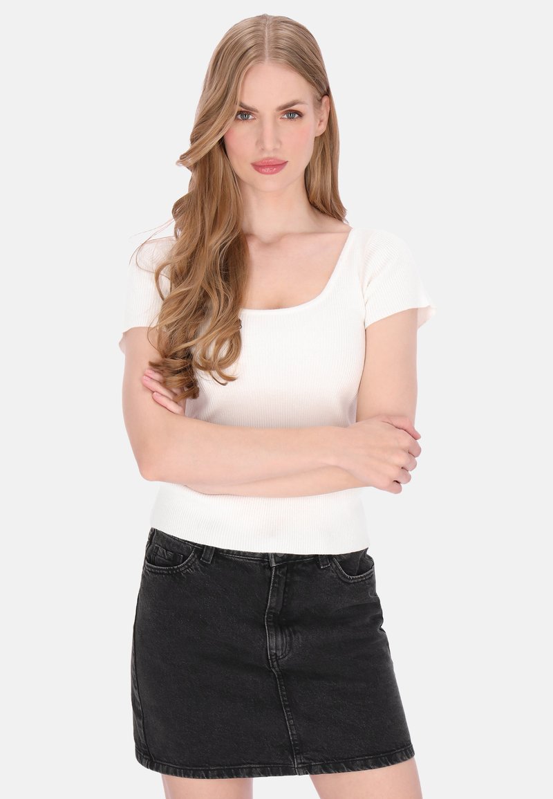 Geribd wit topje met korte mouwen en een vierkante halslijn, gecombineerd met een zwarte denim minirok met een hoge taille en voorzakken.