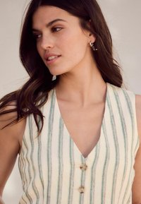 Robe sans manches, à décolleté en V, crème avec des rayures vertes, dotée d'une fermeture à boutons et d'un tissu texturé. Des éléments de design subtils rehaussent le look.