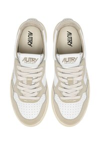 Sneakers beige e bianche con texture traforata, accentuate da dettagli a contrasto, lacci piatti e logo del marchio in rilievo sulla linguetta.