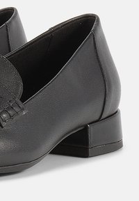 Μαύρα δερμάτινα παπούτσια με χαμηλό τετράγωνο τακούνι, που διαθέτουν ομαλή υφή και διακριτικό πλεκτό σχέδιο στο πάνω μέρος.