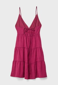 Robe en lin fuchsia avec des fines bretelles, un décolleté en V profond et un devant à cordonnet. Design à volants, texture légère avec une silhouette fluide.