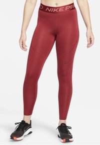 Czerwone legginsy sportowe z wysokim stanem, z czarnym logo Nike. Wykonane z gładkiego, elastycznego materiału, zaprojektowane dla komfortu i swobody ruchów.
