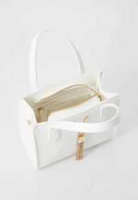 Borsa in finta pelle bianca con due manici, accessori in oro e una tasca interna con zip. Presenta un accento decorativo a frange.