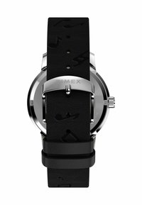 Zegarek Timex z okrągłą srebrną kopertą, czarnym skórzanym paskiem wytłoczonym w nuty muzyczne oraz srebrnym zapięciem na klamrę.