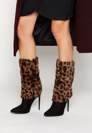 Stivali a punta nera con tacco a stiletto, dotati di polsini in pelliccia sintetica con stampa leopardata e chiusura con zip laterale. Texture liscia e motivi a contrasto.