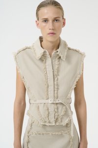Robe sans manches beige avec des bords effilochés, un col et un devant à boutonnière. Présente une taille ceinturée et un design structuré, mettant en valeur un tissu texturé.