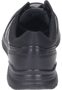 Black athletic shoe with a textured synthetic upper, padded collar, and rubber sole. Features a seamless design and reinforced stitching.