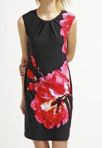 Černé bezramínkové šaty s velkým červeným květinovým potiskem, místem na skládání u výstřihu a upnutým střihem. Hladká textura látky.