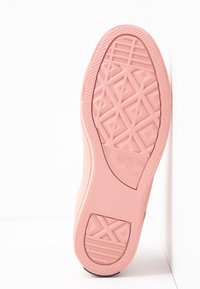 Różowa gumowa podeszwa buta Converse All Star z wyraźnym wzorem i wytłoczonym logo. Gładka faktura z geometrycznymi wzorami.