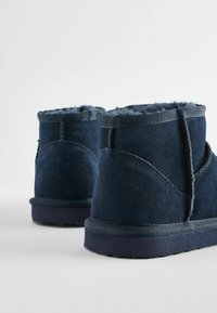 Marina blå mocka vadboots med mjuk pälsfoder, rund tå och texturerad gummisula, med kontrasterande sömmar och robust kant.