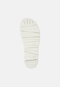 White rubber shoe sole featuring a wave pattern, ridges, and a circular logo with the number 38 embossed. Textured for grip.