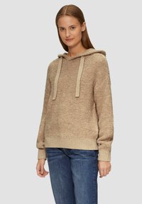 Beige hoodie met textuurstof, geribbelde zoom en manchetten, met beige koorden. Gecombineerd met blauwe jeans.