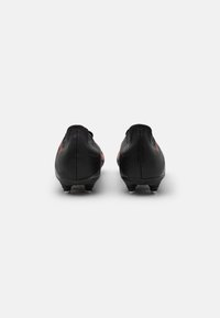 Botas de fútbol negras con una superficie texturizada, que cuentan con un silueta elegante y estrecha, y detalles rojos en los lados. Suela con tacos para mayor tracción.