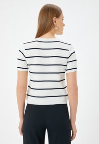 Top de manga corta a rayas en blanco con rayas horizontales en azul marino, con textura acanalada y diseño ajustado. Vista trasera mostrada.