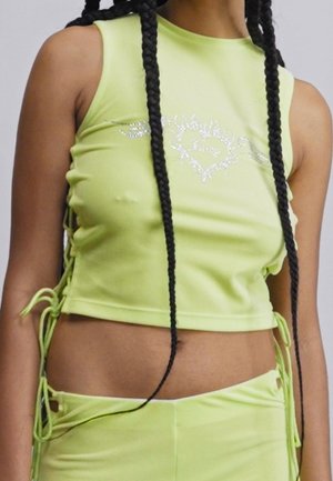 Heller limettengrüner Cropped-Top aus dehnbarem Material mit hohem Kragen, seitlichem Raffung und silbernen Details. Akzente umfassen verstellbare Bindebänder.