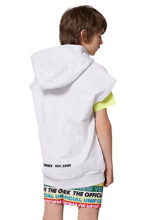 Haut sans manches gris avec capuche, orné d'un logo noir "DKNY EST.1989" au niveau de la taille, associé à un short multicolore à motifs.