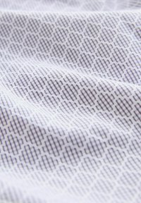 Tissu avec un fond blanc présentant un motif géométrique de hexagones et de lignes verticales dans différentes nuances de gris.