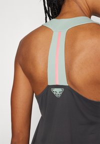 Ärmelloses Sport-Top in Dunkelgrau mit strukturiertem Stoff. Akzentuelle Träger in Hellgrün und Pink, mit einem Logo auf der Rückseite.