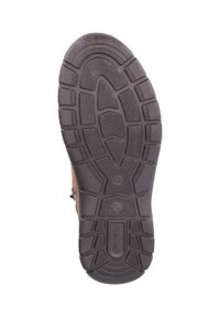Suela de zapato con una superficie de goma texturizada marrón, presentada con un diseño de banda de rodadura patrón para agarre y estabilidad, etiquetada con el nombre de la marca.