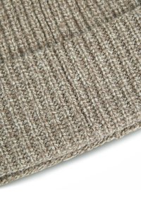 Primo piano di un tessuto a maglia rigata beige e marrone con una texture in filato spesso su sfondo bianco.