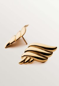 Pendientes en forma de ala de oro con elementos de diseño retorcidos. Superficie suave con un acabado pulido y líneas curvas notables.