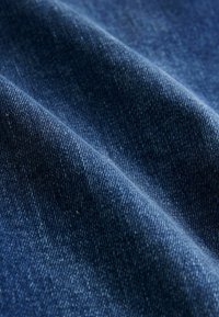 Tumesinise teksariide kangas, millel on sile tekstuur, kergelt läikiv pind ja peened värvitooni variatsioonid, mis on tüüpilised kulunud ilmele.