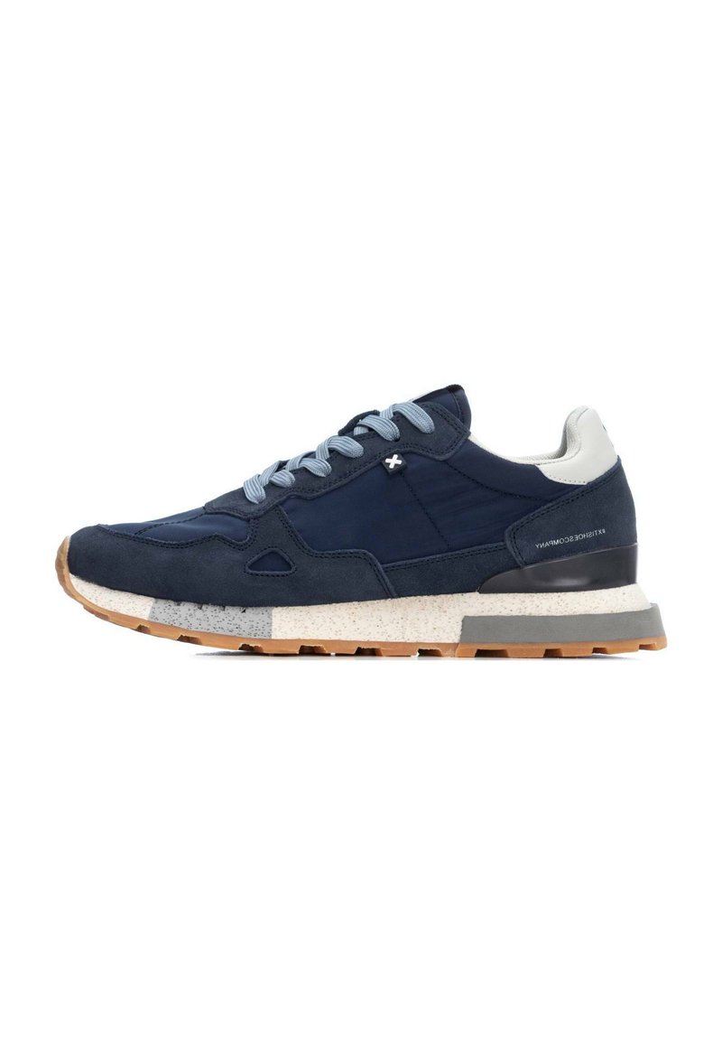 Zapatillas de ante azul marino con cordones azul claro, acentos texturizados, tacón blanco y una entresuela moteada. Suela de goma para mayor agarre y durabilidad.