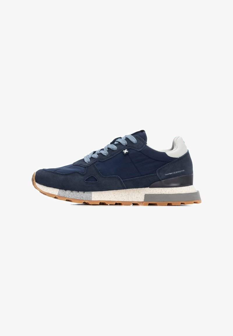 Zapatillas de ante azul marino con cordones azul claro, acentos texturizados, tacón blanco y una entresuela moteada. Suela de goma para mayor agarre y durabilidad.