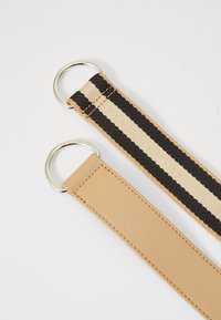 Two belt straps: one in woven black and beige with silver ring, the other in smooth tan leather with a silver ring, both flat and rectangular.