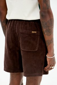 Brune cordfløyelsshorts med en synlig baklomme som har brodert tekst med "BDG." Stoffet har en ribbet og myk tekstur.