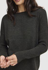 Pull en tricot gris foncé avec une coupe décontractée, un large col et des poignets côtelés. Le matériau semble doux avec une texture subtile. Pas de motifs distincts.