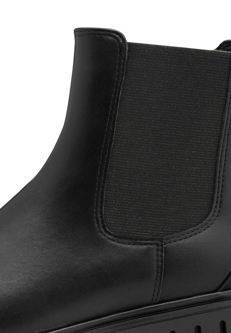 Stivale nero in pelle alla caviglia con pannelli laterali elasticizzati, texture liscia, dettagli cuciti e suola in gomma. Altezza del tacco visibile.
