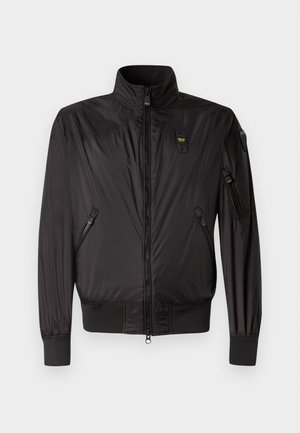 Must musta lukuga jope kõrgema krae, elastsete varrukaotste ja äärega, kahe esiosas oleva lukuga tasku ning lukuga vasaku varruka taskuga.