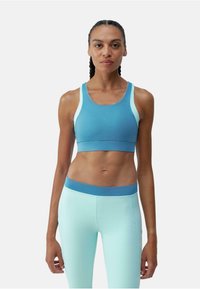 Sutien sport de culoare albastru deschis cu accente albe, asortat cu leggings verde mentă cu talie albastră. Material neted, elastic, design adaptat.