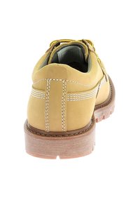 Zapato de cuero amarillo con un collar acolchado, suela de goma y detalles de costura blanca. Presenta cordones redondos y una superficie texturizada.