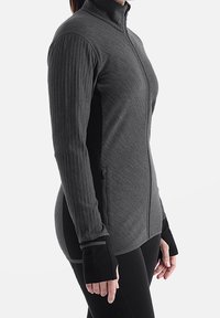 Chaqueta gris de manga larga con cuello alto, tela texturizada, cremalleras laterales y puños con orificio para el pulgar para mayor cobertura y comodidad.